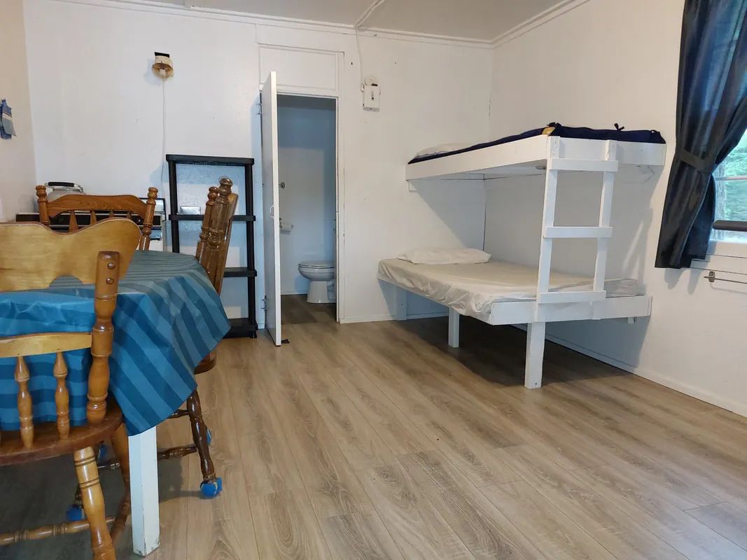 Interior view of cabin 5 including a dining table, a bunk bed, and an adjoining bathroom.