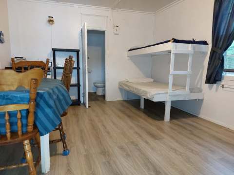 Interior view of cabin 5 including a dining table, a bunk bed, and an adjoining bathroom.
