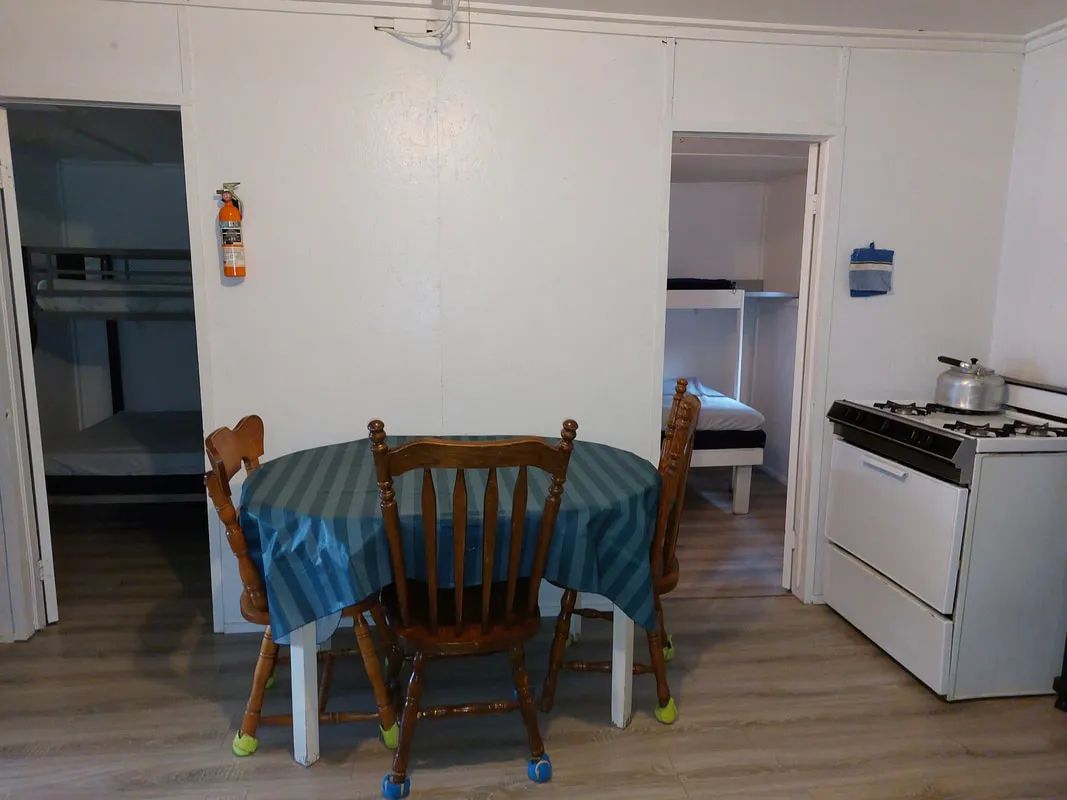View of the open area including the dining table and stove, with access to the bedrooms.