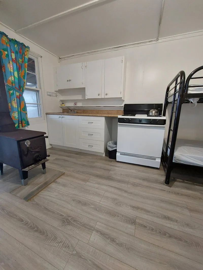 La cuisinette du chalet comprend un poêle, des espaces de rangement et un poêle à bois.