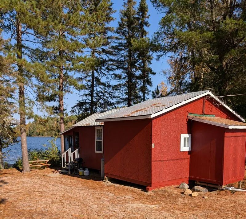 Le chalet 1 est situé en bordure de lac, entouré d'arbres.