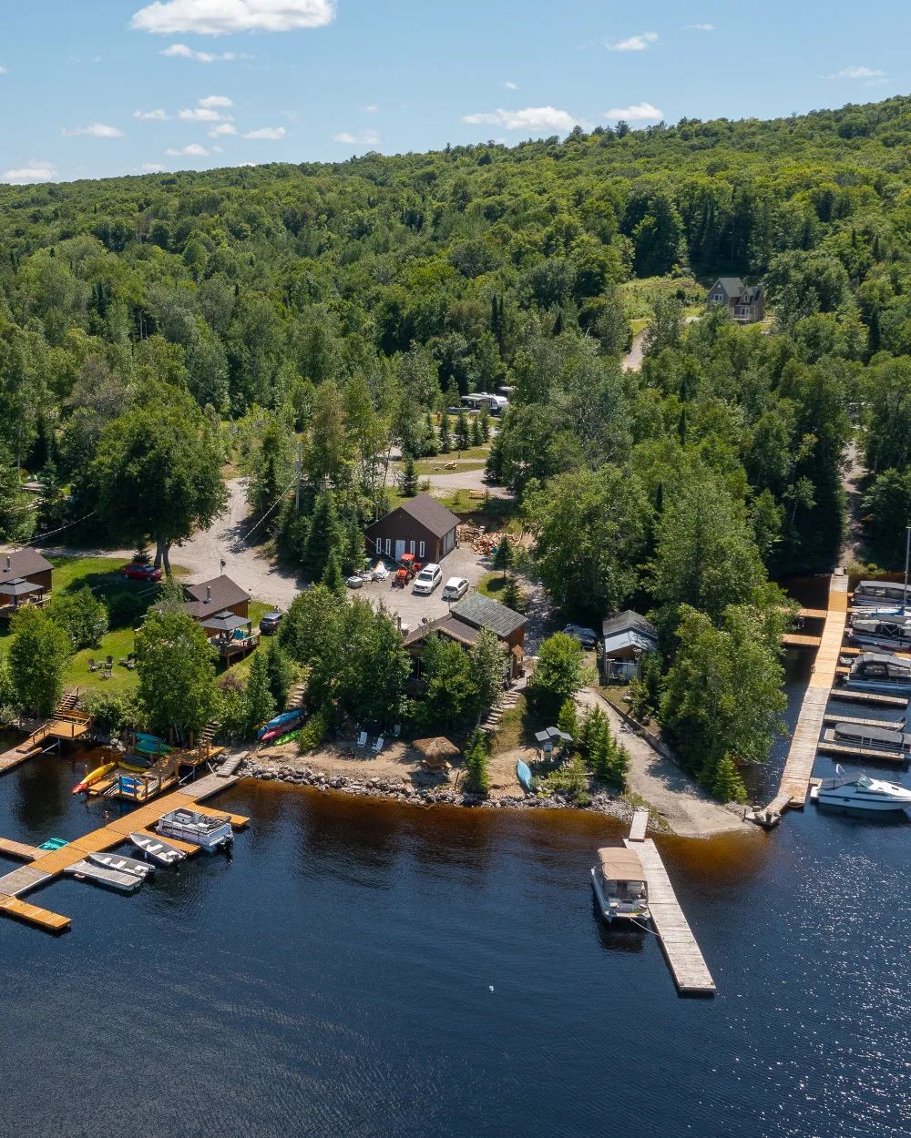 Vue aérienne de la pourvoirie avec ses chalets en bordure de lac et ses installations nautiques.