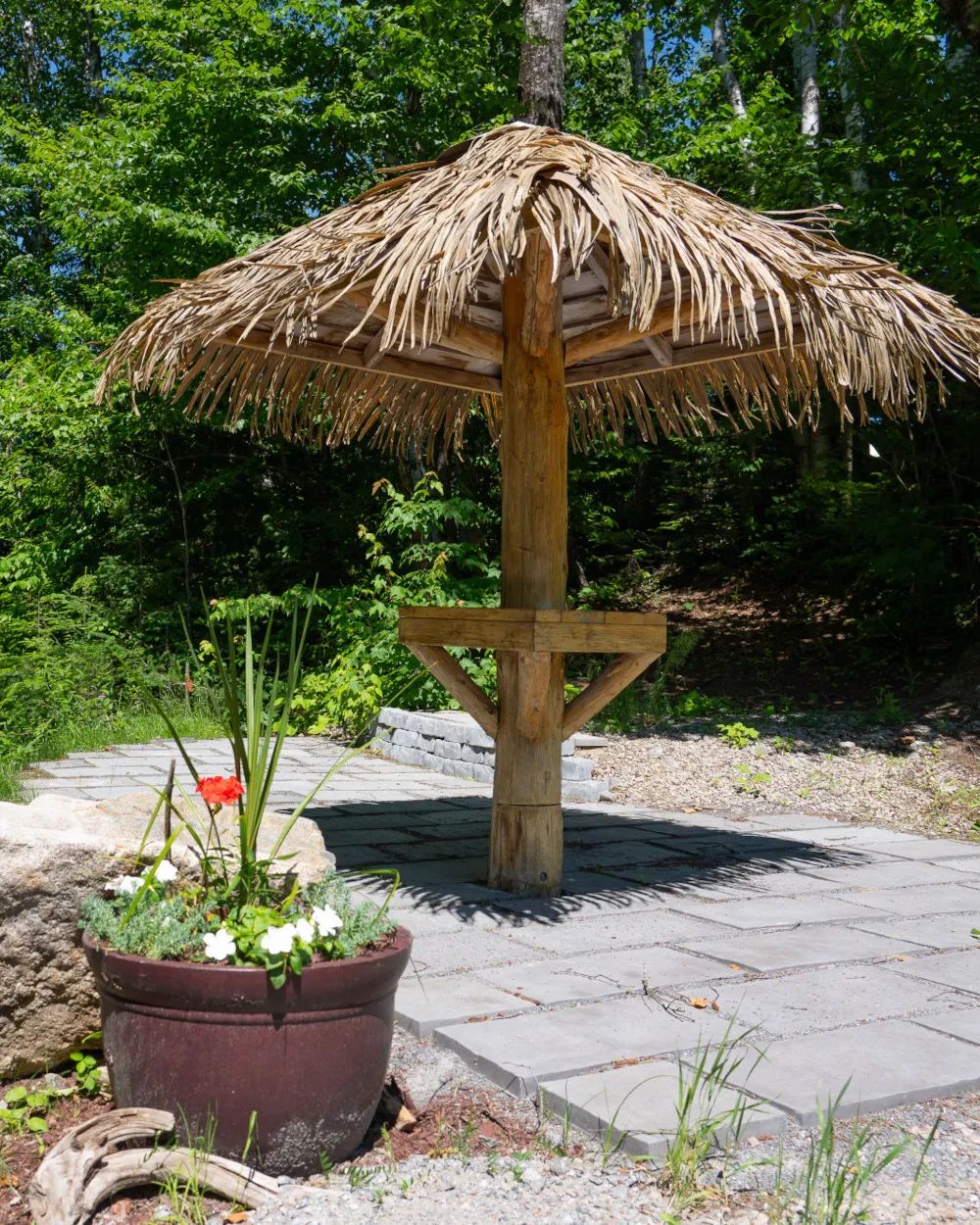 Une zone de repos aménagée avec un parasol en chaume dans l'espace camping.