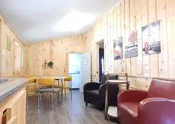 Espace salon et coin repas aménagé avec des murs en lambris de bois naturel.