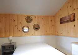 Une chambre lumineuse avec murs en lambris de bois naturel et décoration murale.