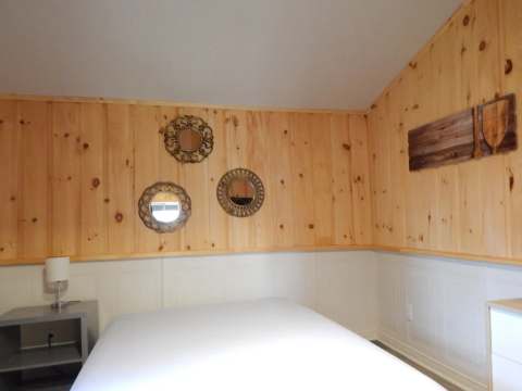 Vue de l'intérieur d'une chambre à coucher avec un lit et des murs en bois lambrissé.