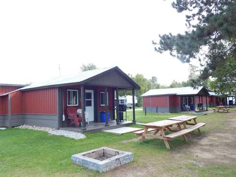 Vue extérieure des chalets avec tables de pique-nique et espaces pour feu de camp.