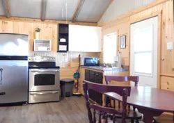 La cuisine équipée du chalet 2 comprend une cuisinière, un réfrigérateur et un coin repas.