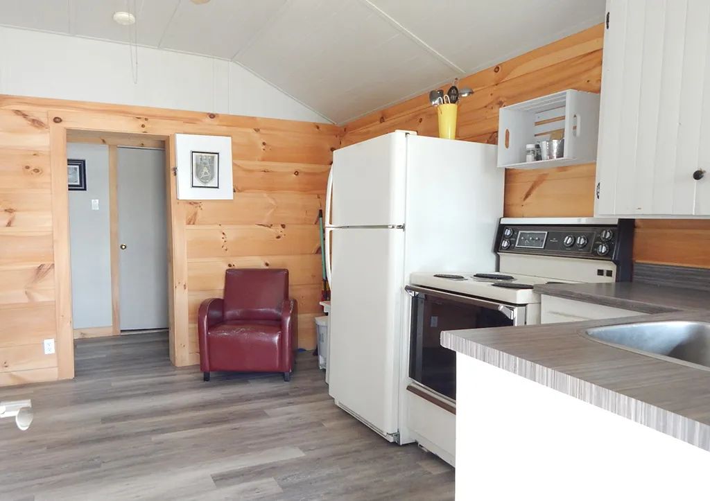 La cuisine équipée du chalet 5 comprend une cuisinière et un réfrigérateur dans un décor en bois.