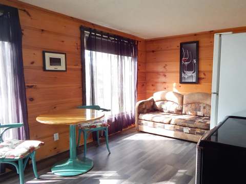 Coin repas et salon aménagés dans le chalet 6 avec murs en lambris de bois.