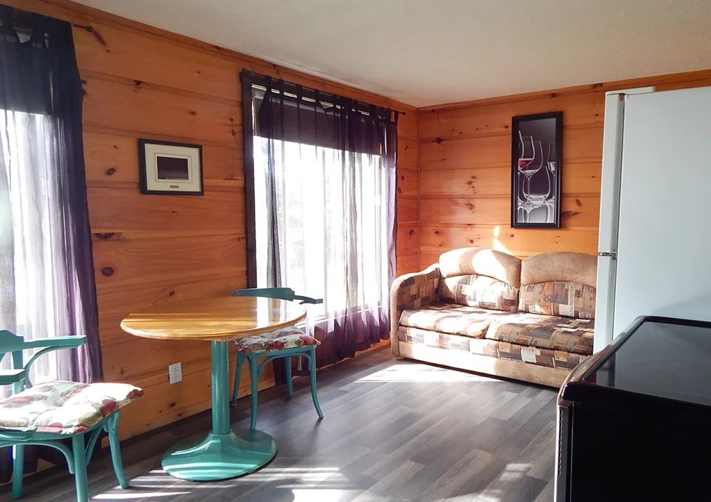 Coin repas et salon aménagés dans le chalet 6 avec murs en lambris de bois.