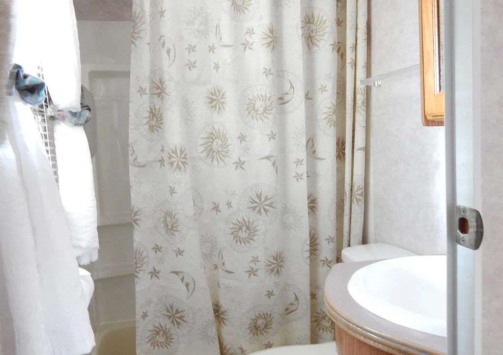 Vue de la petite salle de bain fonctionnelle de la roulotte avec douche et lavabo.