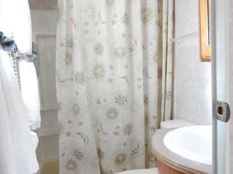 Vue de la petite salle de bain fonctionnelle de la roulotte avec douche et lavabo.