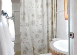 La salle de bain de la roulotte comprend une douche avec rideau et un lavabo.