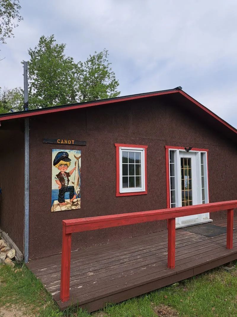 Exterior view of Le Canot cabin with its wooden deck and themed wall decor.