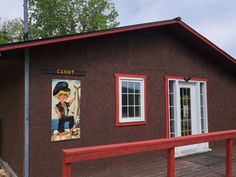 Exterior view of Le Canot cabin with its wooden deck and themed wall decor.