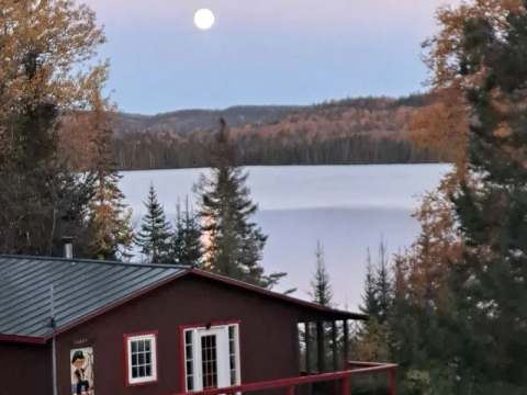 View of Le Canot cottage by the lake under the full moon light.