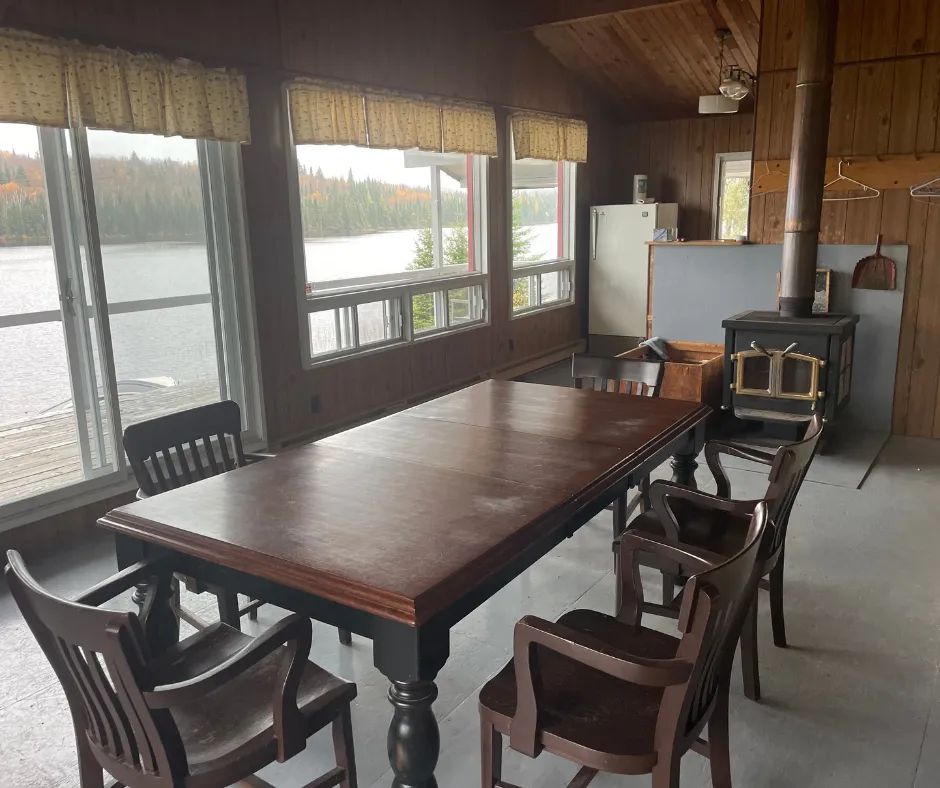 La salle à manger du chalet Le Familial avec vue sur le lac et poêle à bois.