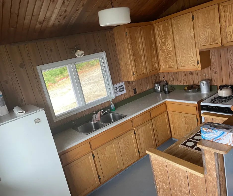 La cuisine fonctionnelle du chalet Le Familial dispose d'armoires en bois et d'une cuisinière.