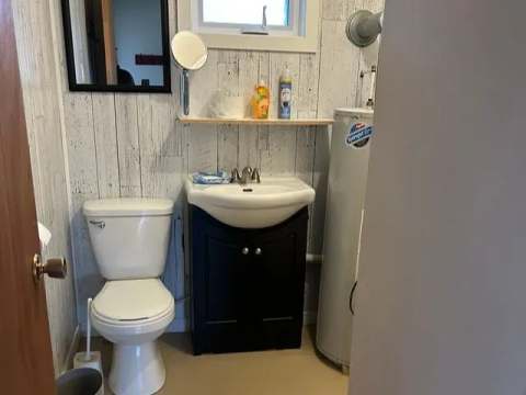 La salle de bain du lodge comprend une toilette et un lavabo avec meuble de rangement.