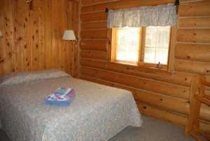 Une chambre confortable avec un lit et des murs en bois rond au Aspen Lodge.