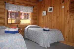 Cette chambre rustique en bois rond comprend deux lits simples avec literie et serviettes fournies.