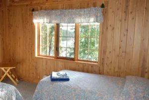Vue de la chambre à coucher avec ses lits et sa fenêtre donnant sur la forêt.