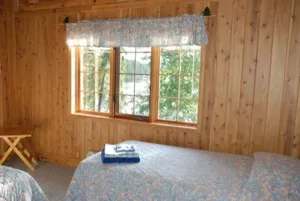 Vue de la chambre à coucher avec ses lits et sa fenêtre donnant sur la forêt.