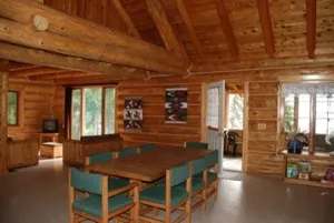 La salle à manger et le salon ouverts du chalet Evergreen offrent une ambiance rustique en bois rond.
