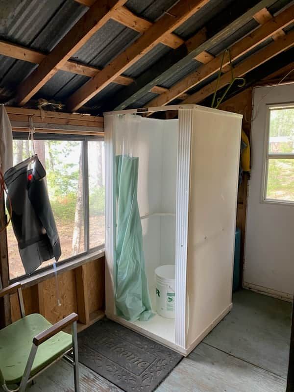 Une douche fermée située dans une véranda rustique attenante au chalet.