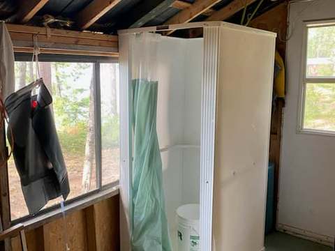 Une douche fermée située dans une véranda rustique attenante au chalet.