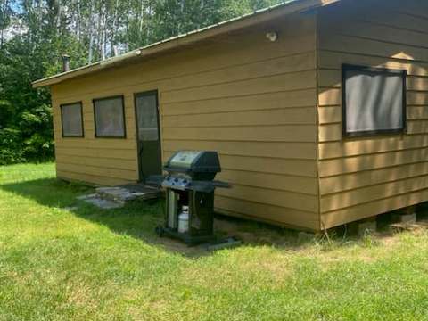 Vue latérale du chalet avec un barbecue disponible à l'extérieur.