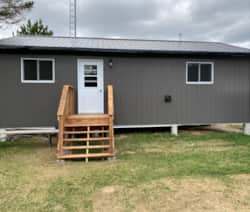 Vue latérale du chalet avec ses escaliers en bois menant à l'entrée principale.