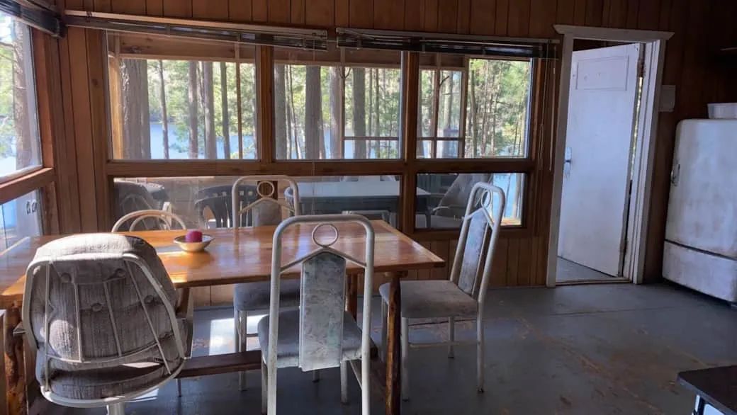 La salle à manger du chalet dispose d'une table avec vue sur la forêt et le lac.