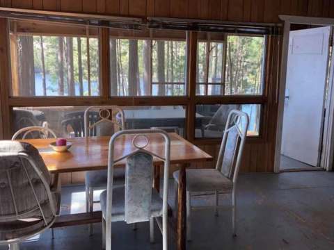 La salle à manger du chalet dispose d'une table avec vue sur la forêt et le lac.
