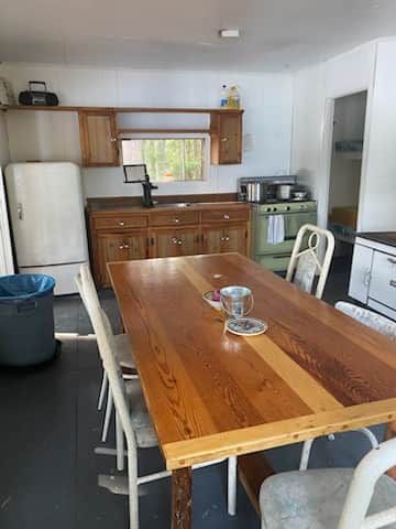 La cuisine équipée est adjacente à la salle à manger avec sa table en bois rustique.