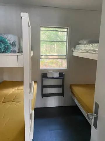Cette chambre comporte des lits superposés avec une vue sur la forêt par la fenêtre.