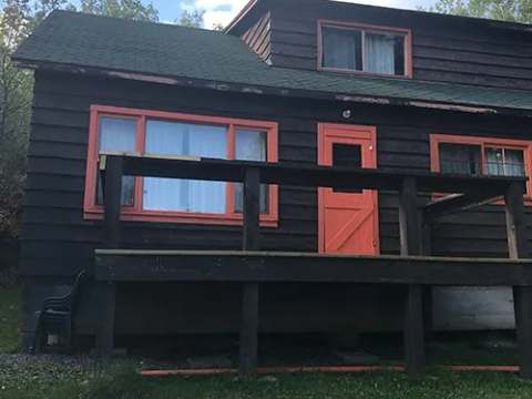 Exterior view of cabin number one featuring its deck and orange trim.