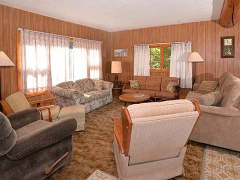The cabin living room is furnished with several comfortable armchairs and sofas.
