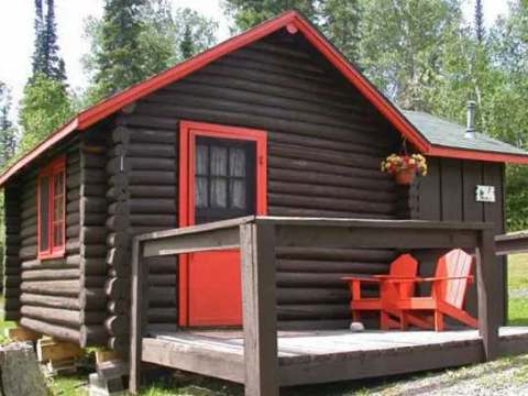 Vue extérieure du chalet sept avec sa galerie en bois et ses chaises rouges.