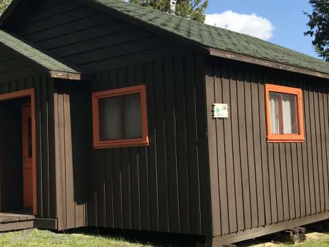 Vue extérieure du chalet 14, un bâtiment en bois avec des cadres de fenêtres oranges.