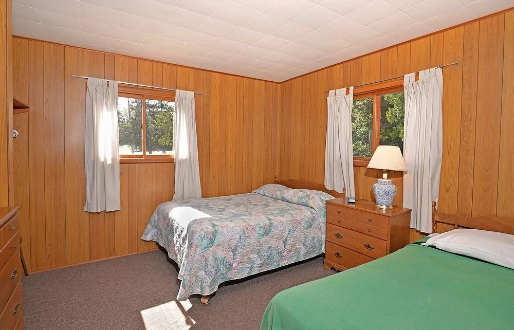 Cette chambre rustique du chalet 14 dispose de deux lits et de murs lambrissés en bois.