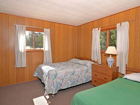Cette chambre rustique du chalet 14 dispose de deux lits et de murs lambrissés en bois.