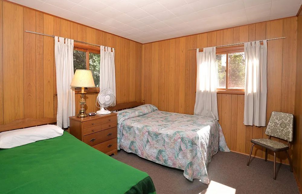 Cette chambre à coucher du chalet comprend deux lits simples avec des fenêtres lumineuses.