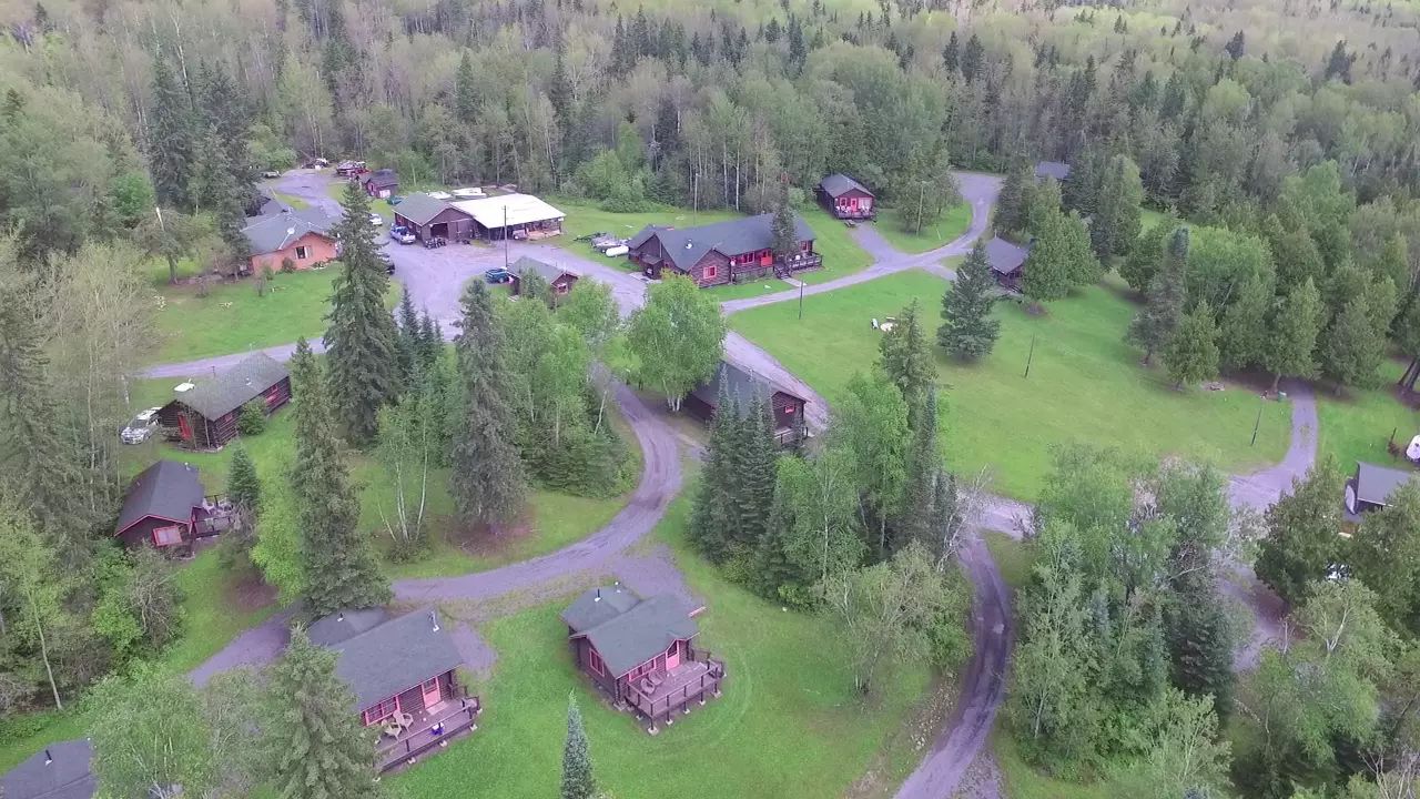 Vue aérienne de l'ensemble des chalets situés sur le terrain boisé de la pourvoirie.