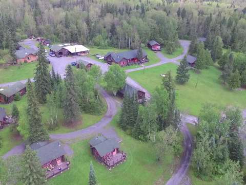 Vue aérienne de l'ensemble des chalets situés sur le terrain boisé de la pourvoirie.
