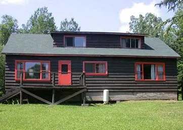 Exterior view of cabin 1A with its dark wood siding and red trim.