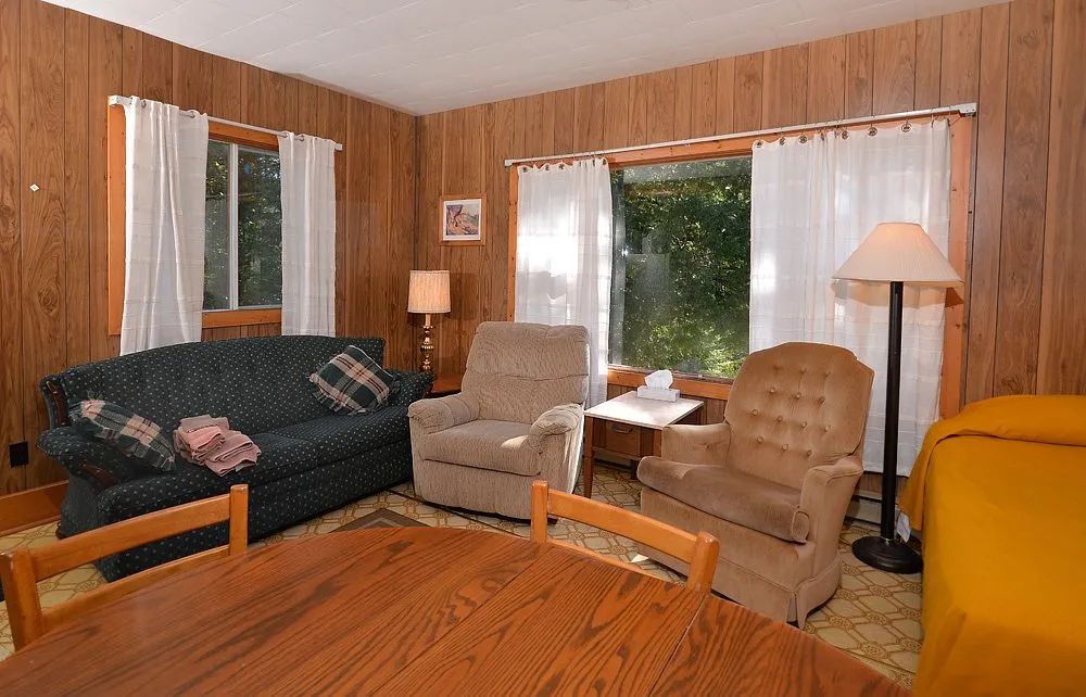 The cabin living area includes a sofa, comfortable armchairs, and a dining table.