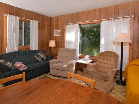 The cabin living area includes a sofa, comfortable armchairs, and a dining table.