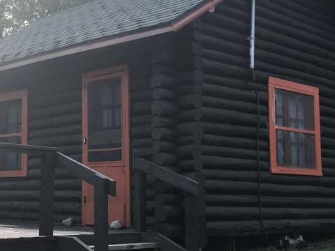 Exterior view of cabin number four featuring log walls and colorful window frames.